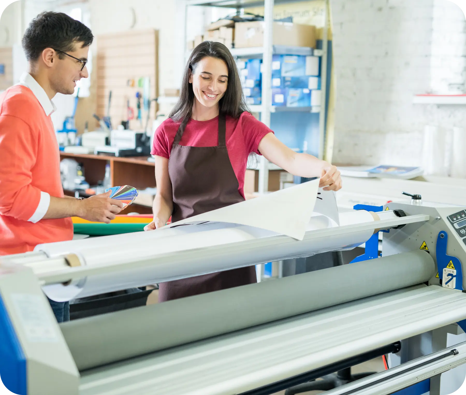 Two people working with large printer machine.
